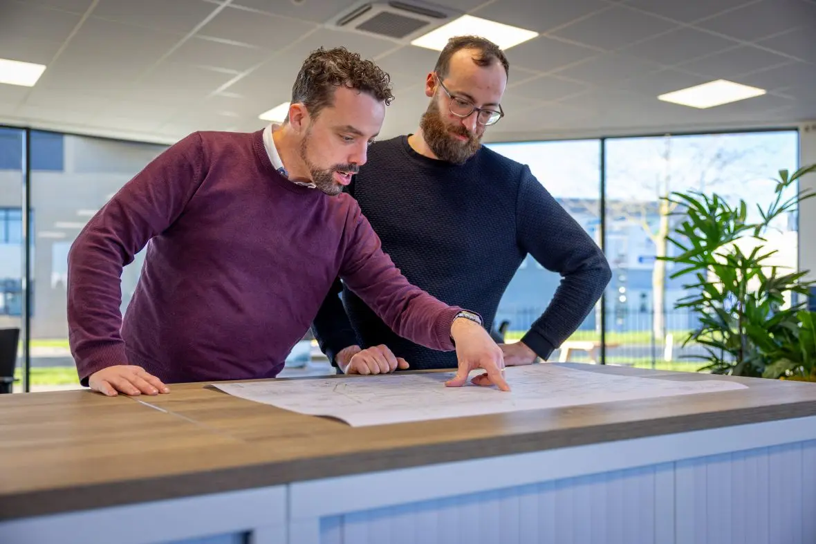 Twee collega's bij bouwtekening op kantoor